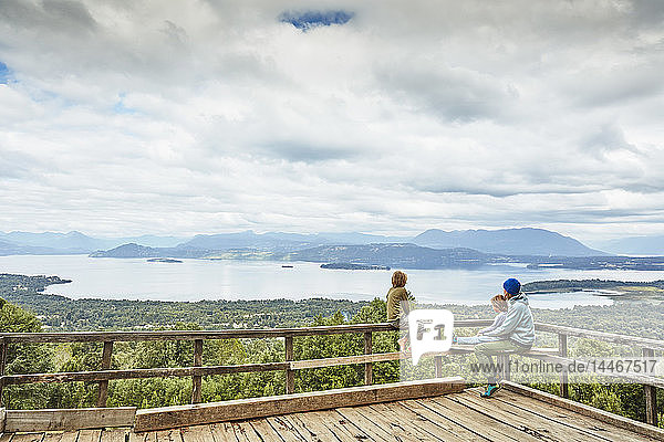 Chile  Puren  Nahuelbuta-Nationalpark  Frau mit zwei Söhnen sitzt auf der Aussichtsterrasse mit Blick auf den See