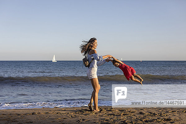Mother and daughter having fun on the beach  pretending to fly