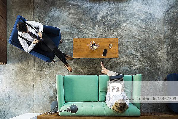 Top view of business colleagues working on laptop and smartphone in coworking space