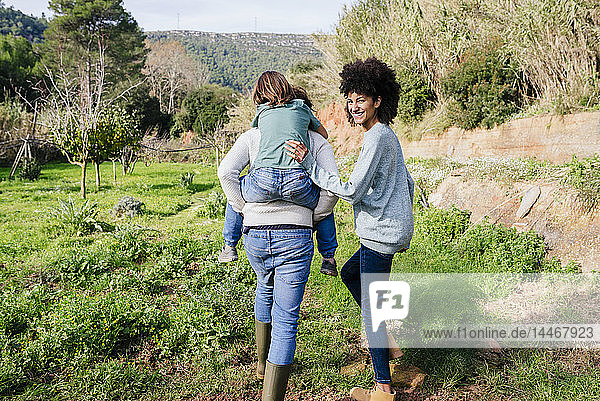 Glückliche Familie beim Spaziergang auf dem Land  Vater trägt Sohn huckepack