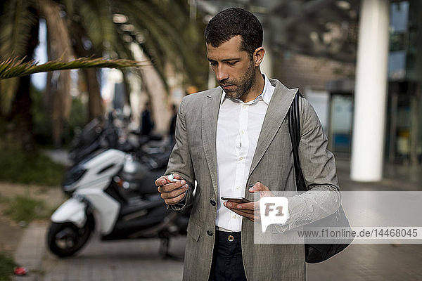 Businessman with cell phone in the city applying earbuds