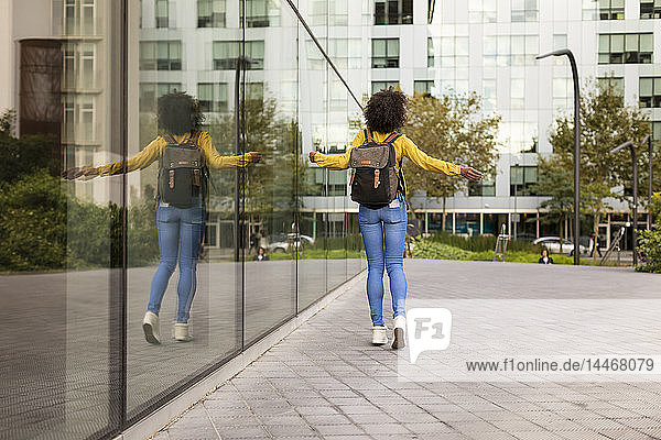 Rückenansicht einer Frau mit Rucksack beim Spaziergang in der Stadt