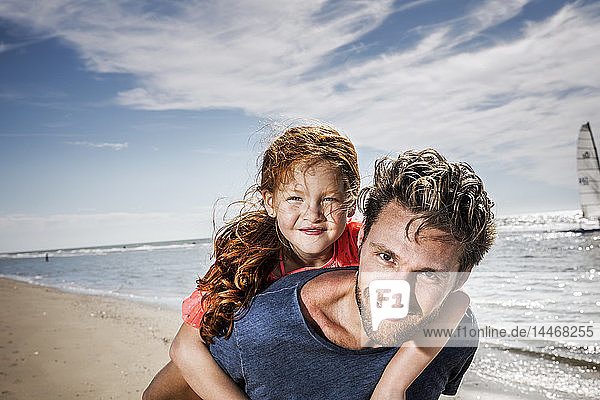 Niederlande  Zandvoort  Porträt eines lächelnden Vaters mit Tochter am Strand
