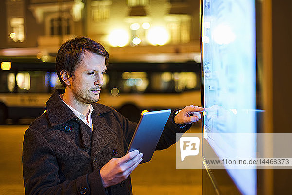 Businessman using digital tablet at night in the city