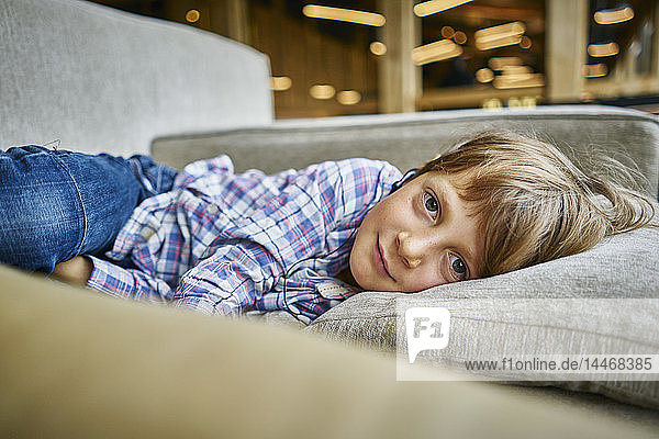 Portrait of boy lying on couch with earphones