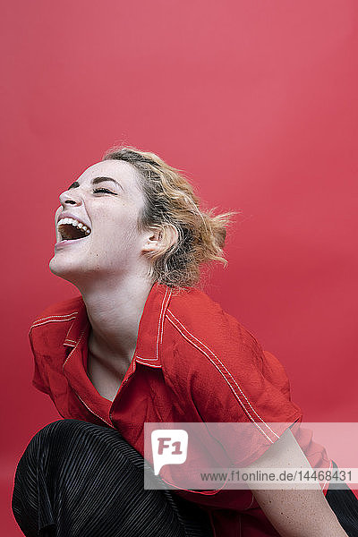 Lachende junge Frau liniert vor rotem Hintergrund