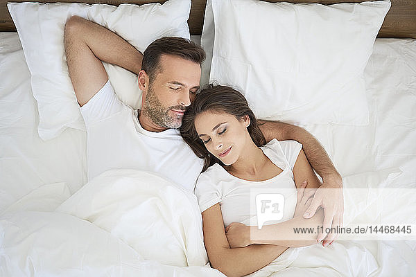 Couple lying in bed  sleeping with arms around