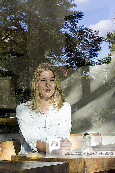 Porträt einer blonden Frau in einem Cafe  die aus dem Fenster schaut
