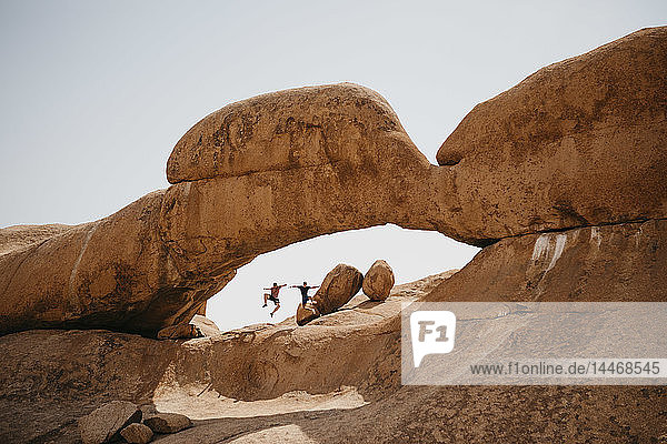 Namibia  Spitzkoppe  zwei Freunde springen auf eine Felsformation