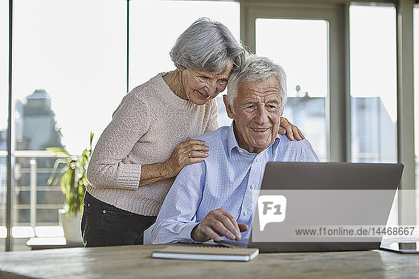 Portrait eines lächelnden älteren Paares mit Laptop