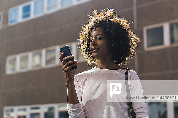 Young casual businesswoman using smartphone in the city