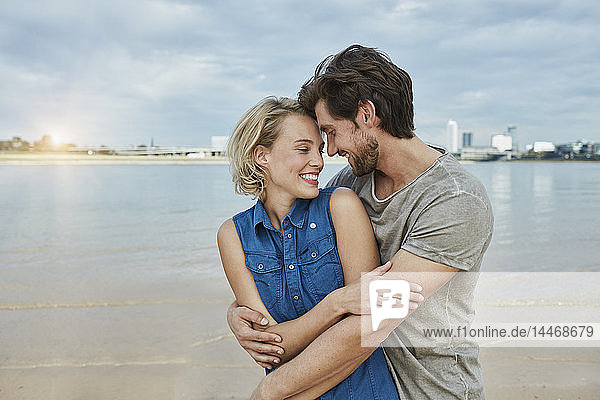 Glückliches junges Paar umarmt sich am Flussufer