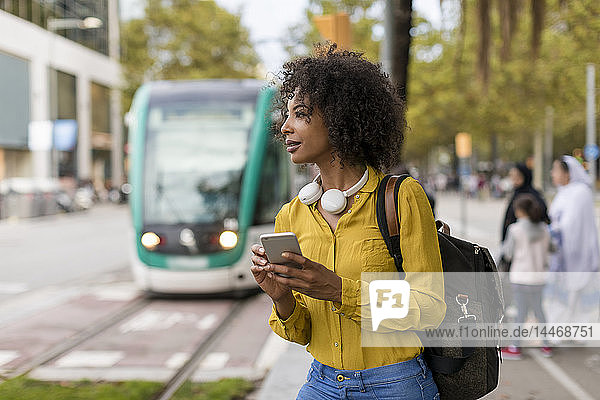 Frau mit Rucksack und Kopfhörern mit Smartphone in der Stadt