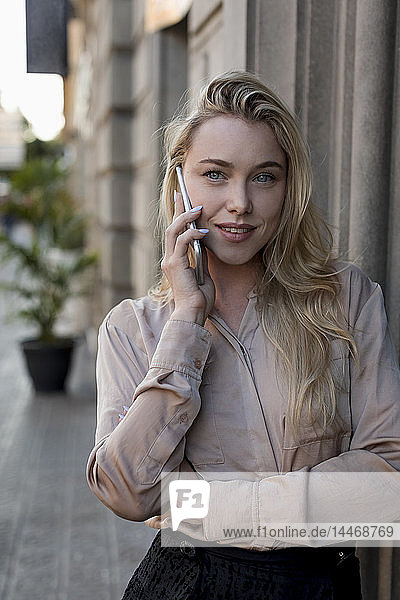 Portrait of beautiful young businesswoman on cell phone in the city