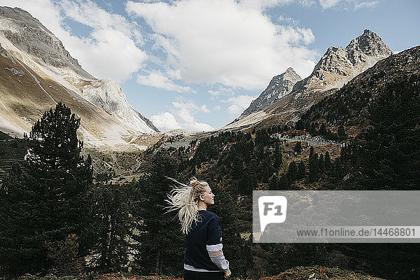 Schweiz  Graubünden  Albulapass  junge Frau mit windgepeitschtem Haar in Berglandschaft stehend
