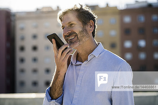 Smiling mature man using cell phone in the city