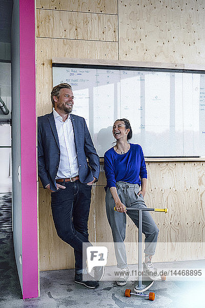 Mature man and his assistent with scooter  standing in office in front of white board