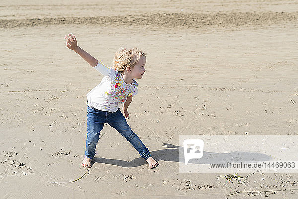 Verspieltes kleines Mädchen  das am Strand posiert