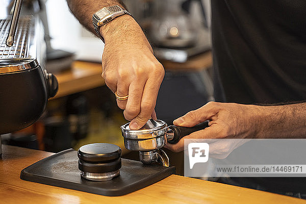 Nahaufnahme eines Barista  der den Siebträger einer Kaffeemaschine in einem Café vorbereitet
