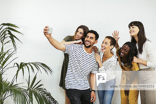 Verspielte Kollegen stehen an der Ziegelmauer und nehmen sich ein Selfie