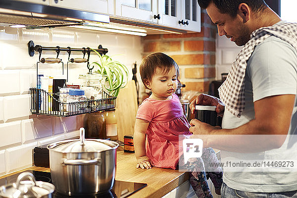Father and baby girl cooking together in kitchen at home