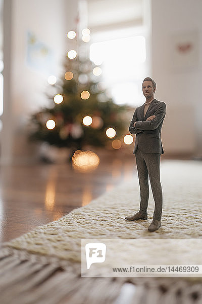 Geschäftsmann-Figur  die zu Hause neben einem Weihnachtsbaum steht