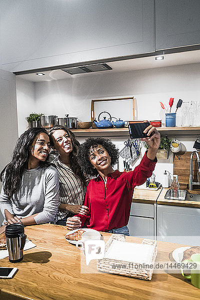 Drei glückliche Frauen posieren für ein Selfie bei Tisch