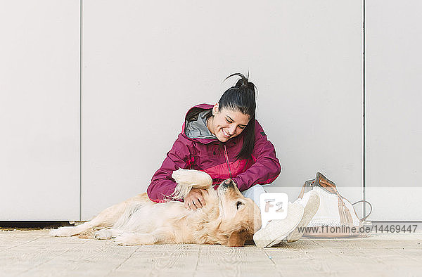 Glückliche junge Frau streichelt und spielt mit ihrem Golden Retriever-Hund