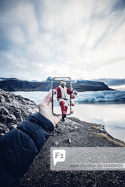 Island  als Weihnachtsmann verkleideter Mann kommt aus einem Handy