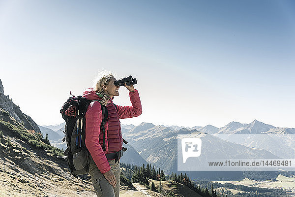 Österreich  Tirol  Frau  die während einer Wanderung durch ein Fernglas schaut
