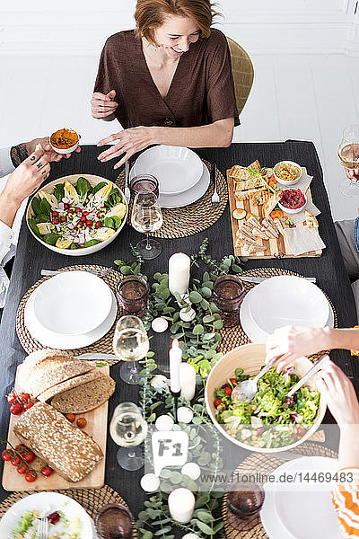 Friends sitting at laid table  enjoying their dinner party  view from above