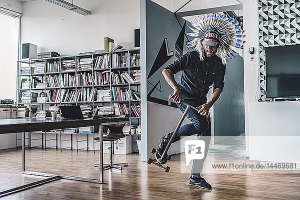 Man wearing Indian headdress and VR glasses in office  using kick scooter