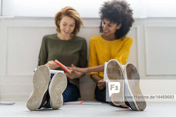 Colleagues in coworking space discussing business solutions  sitting on floor