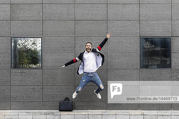 Aufgeregter Geschäftsmann springt vor Gebäude
