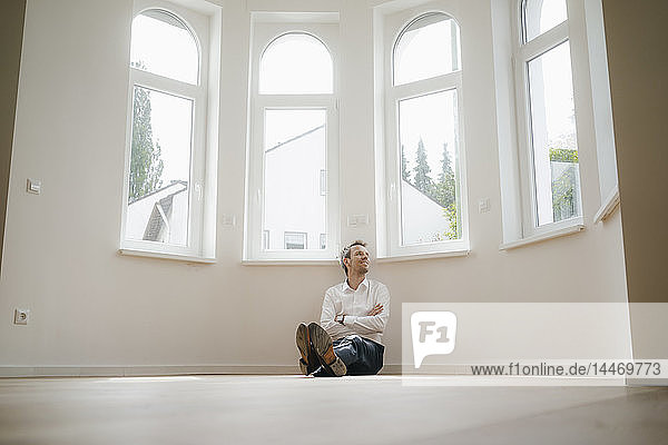 Businessman sitting on ground of his newly refurbished home  looking happy