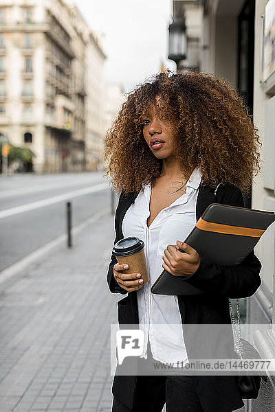 Young woman with laptop bag and coffee to go in the city