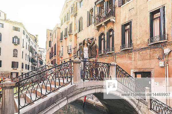 Italien  Venedig  junges Paar steht auf einer kleinen Brücke und erkundet die Stadt