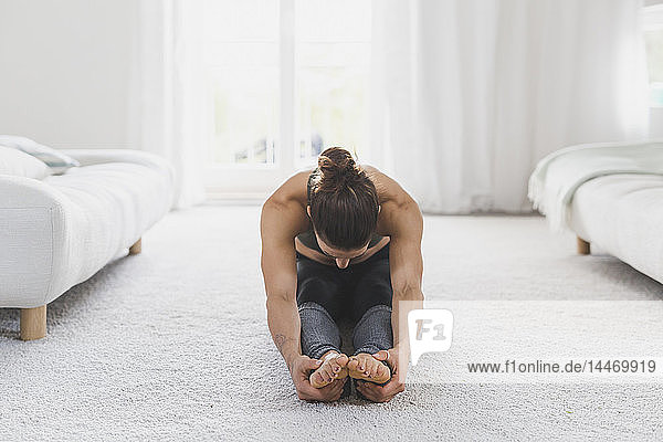 Frau sitzt auf dem Boden und praktiziert Yoga