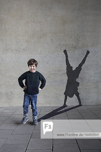 Deutschland  Düsseldorf  Porträt eines lächelnden kleinen Jungen und Schatten des Düsseldorfer Radschlägers an der Wand