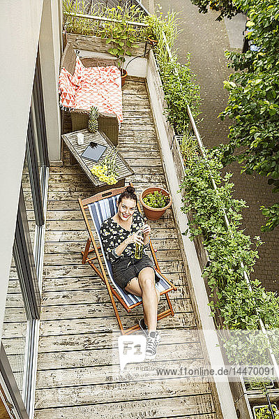 Young woman sitting in deck chair  relaxing on her balcony
