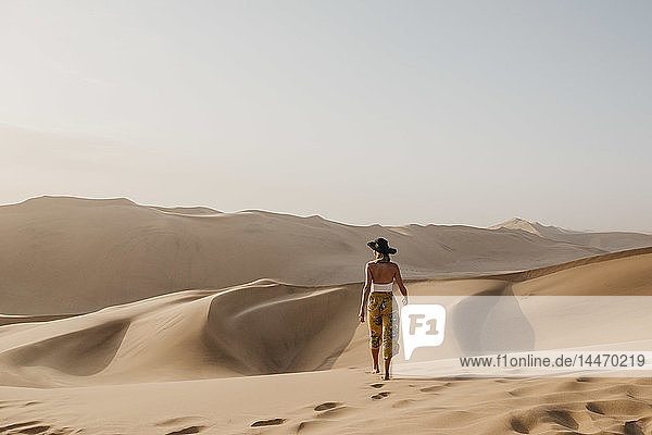 Namibia  Namib  back view of woman walking barefoot on desert dune