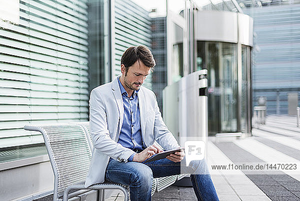 Businessman sitting on a bench  using digital tablet