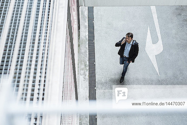 Businessman walking in parking garage  using mobile phone