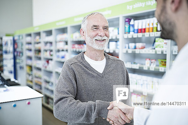 Pharmacist and customer shaking hands in pharmacy