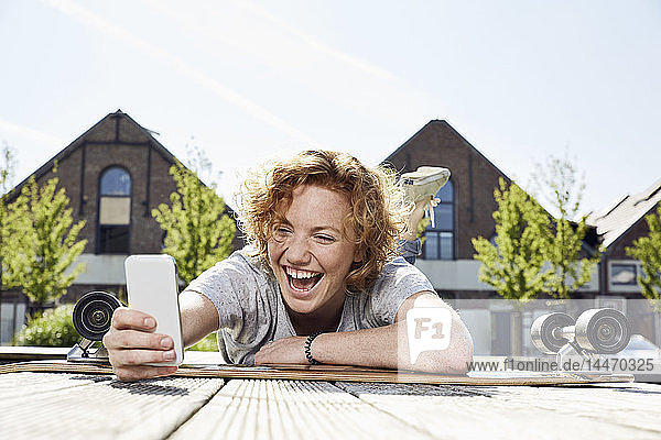 Glückliche junge Frau benutzt Smartphone in städtischer Umgebung