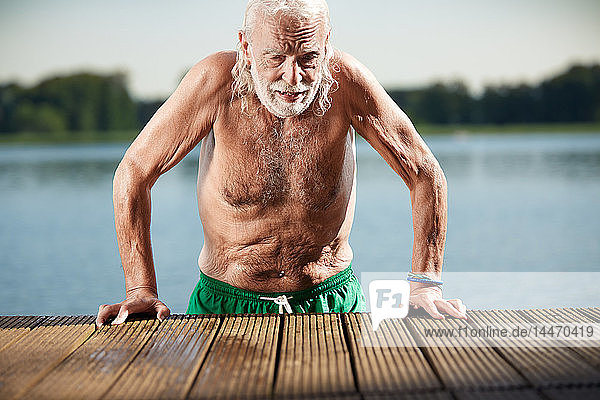 Porträt eines älteren Mannes  der sich am Steg am See anlehnt