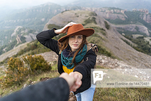 Frau mit Hut  auf Berg stehend  sich an Männerhand haltend