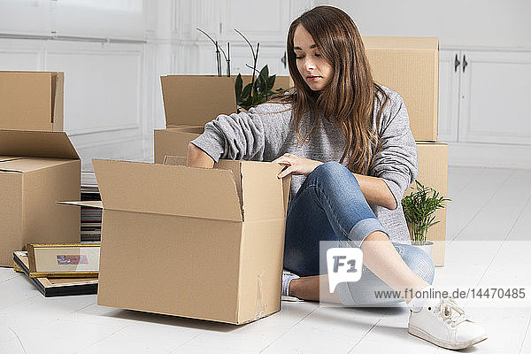 Woman sitting on the floor packing cardboard boxes