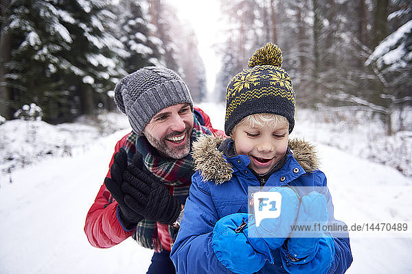 Portrait of father and little son together in winter forest