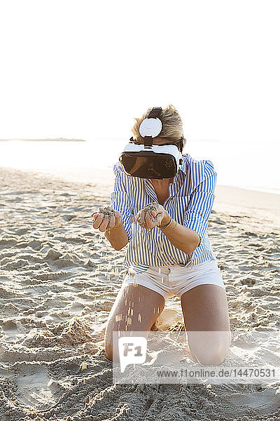 Thailand  Frau mit Virtual-Reality-Brille am Strand im Morgenlicht